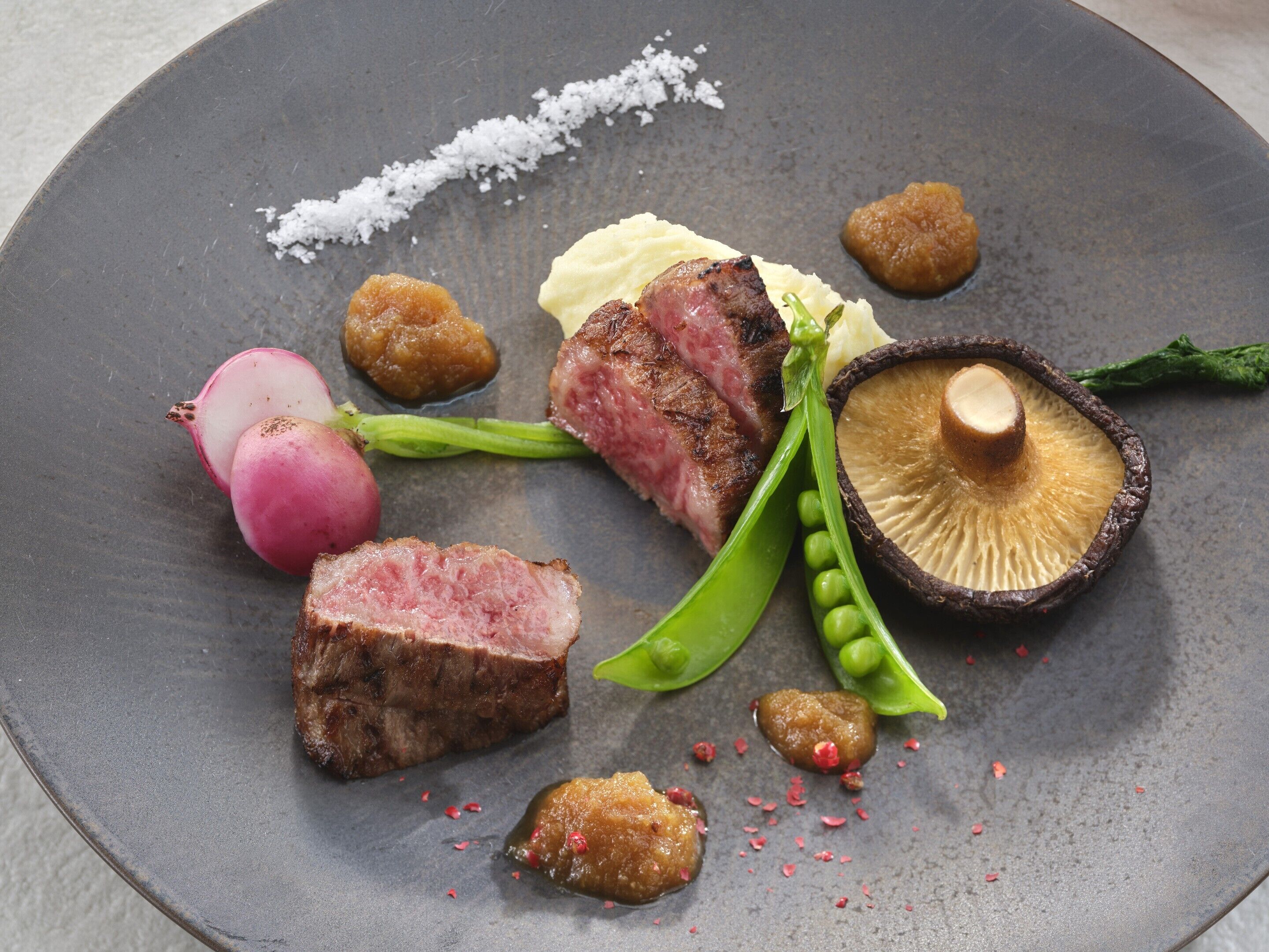 A plate with various food items including meat, radish, peas, and a mushroom.