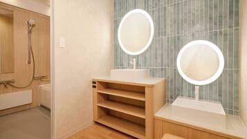 A modern bathroom with a shower, two sinks with illuminated mirrors, and a wooden vanity.