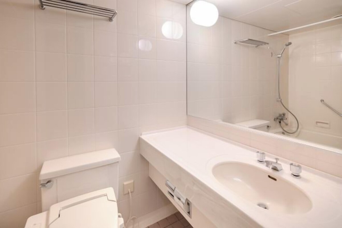 A modern bathroom with a white sink, mirror, and toilet.