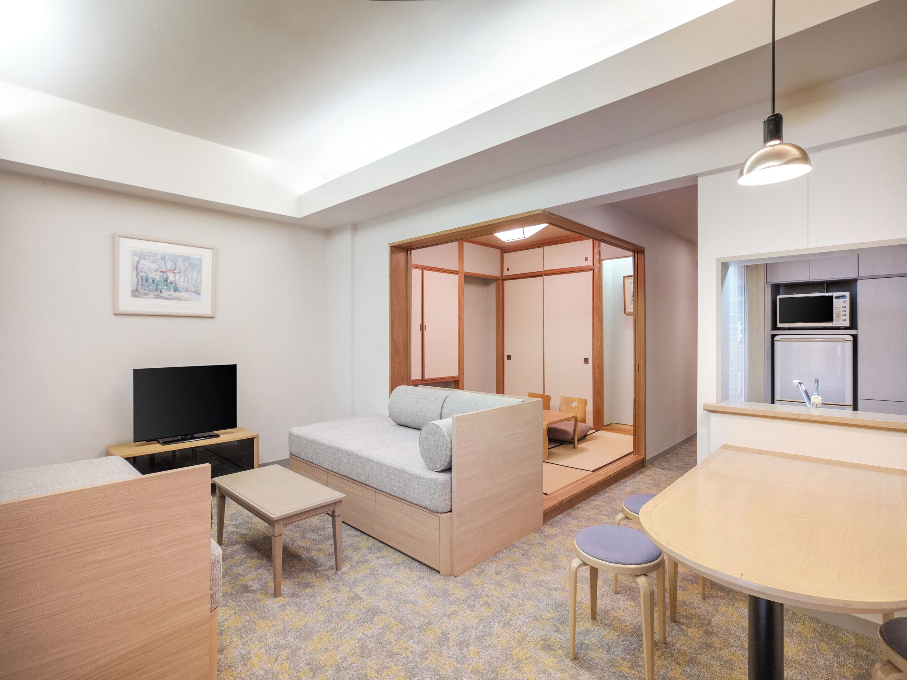 Un espacio habitable compacto con sofá, televisor, mesita y kitchenette.