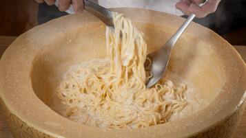 A person preparing a dish with noodles in a large bowl.