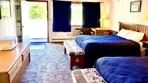 A hotel room with two beds, a desk, a chair, a microwave, and a window with curtains. - Forest Lake Motel (Grand Rapids)