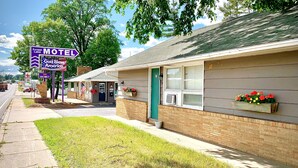 A motel with a green door, a small porch, and flower boxes. - Forest Lake Motel (Grand Rapids)