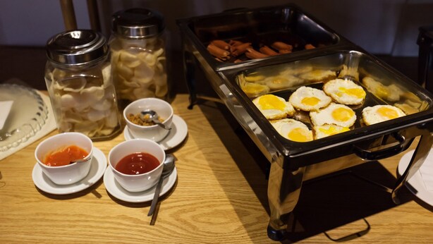 A buffet with various food items including eggs, sausages, and condiments. - Liberty Hotel Thamrin Jakarta (Jakarta)