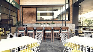 An outdoor cafe with brick walls, large windows, and a variety of seating including tables and chairs. - Liberty Hotel Thamrin Jakarta (Jakarta)