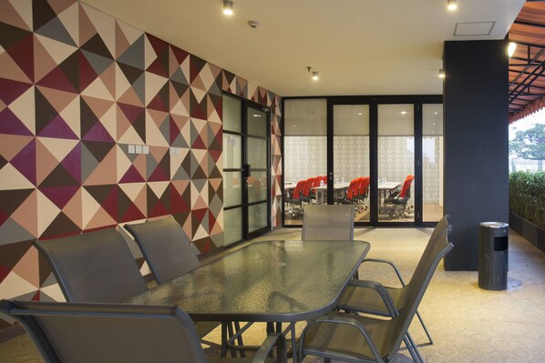 Une salle de conférence moderne dotée d’une table en verre, de chaises en métal et d’un mur orné d’un motif géométrique.