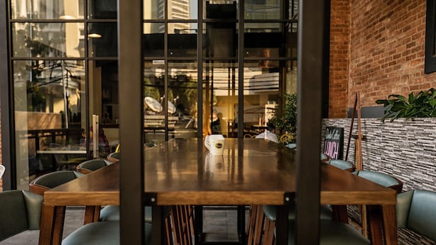A conference room with a large wooden table surrounded by chairs, a glass partition, and a brick wall. - Liberty Hotel Thamrin Jakarta (Jakarta)