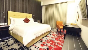 A hotel room with a bed, a desk, a chair, a TV, and a window with curtains. - Liberty Hotel Thamrin Jakarta (Jakarta)