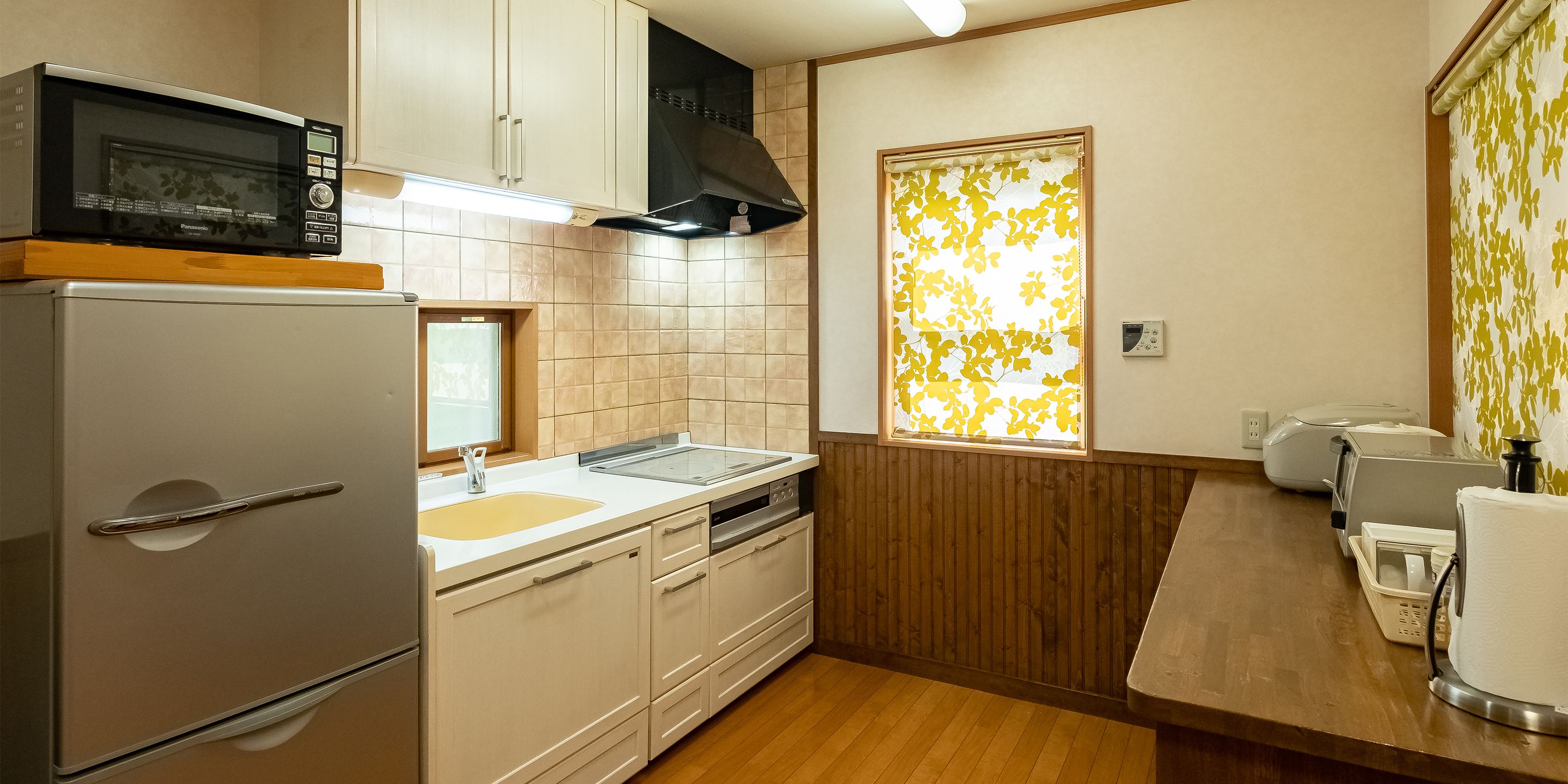 Una cocina compacta con refrigerador, microondas, pileta y encimera de madera.