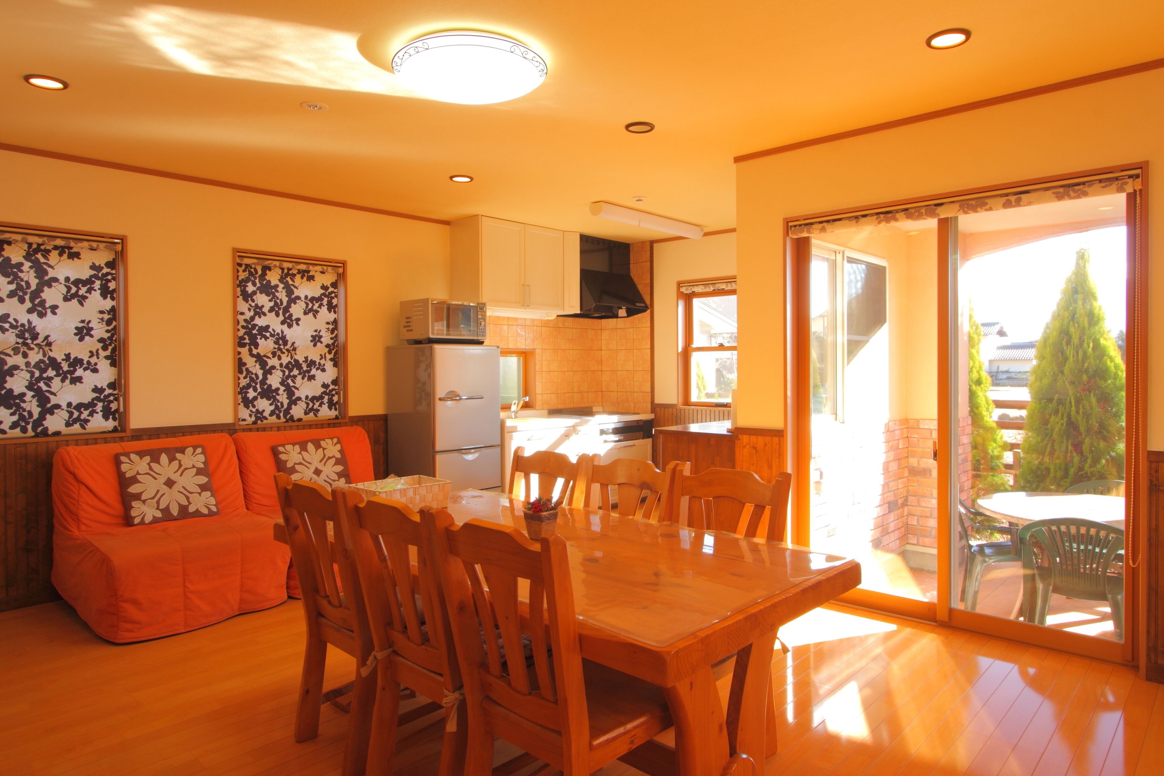 A spacious dining area with a wooden table and chairs, a kitchen in the background, and a sliding glass door leading to an outdoor patio.