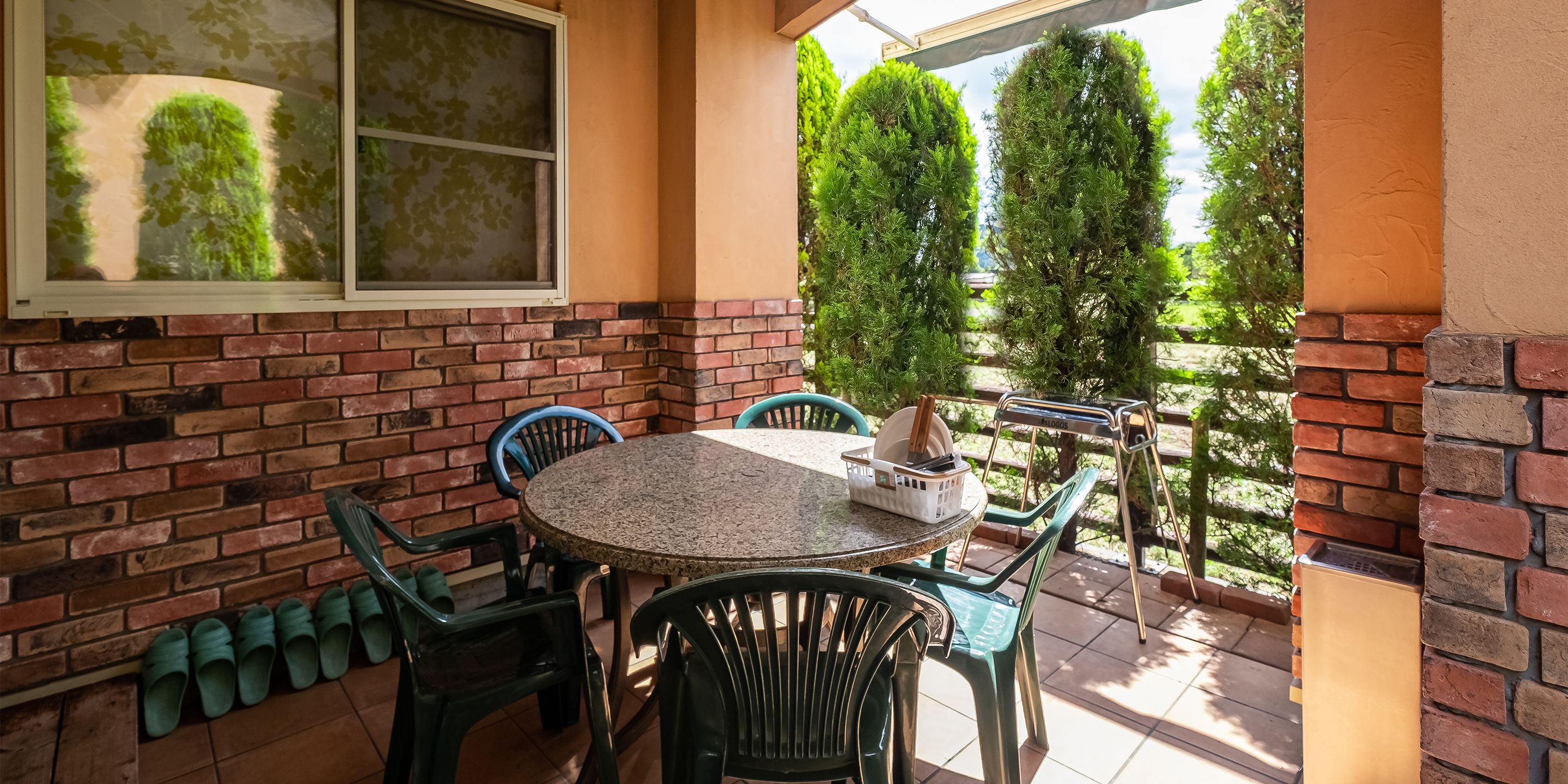 A patio with a round table, chairs, and a brick wall.