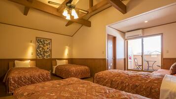 A hotel room with three beds, wooden beams on the ceiling, a ceiling fan, and a large window with a view of the outside.