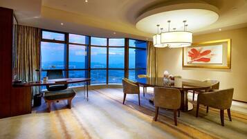 A hotel room with a large window offering a view of the cityscape and a table with chairs.