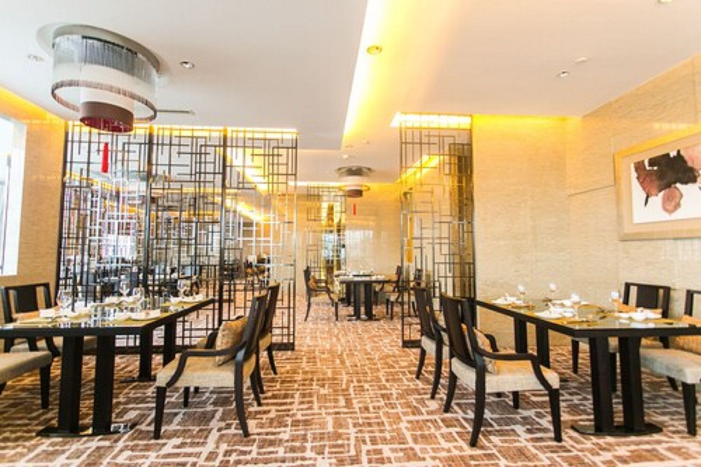 Un restaurante con varias mesas y sillas, un piso con diseño y un techo de estilo moderno.