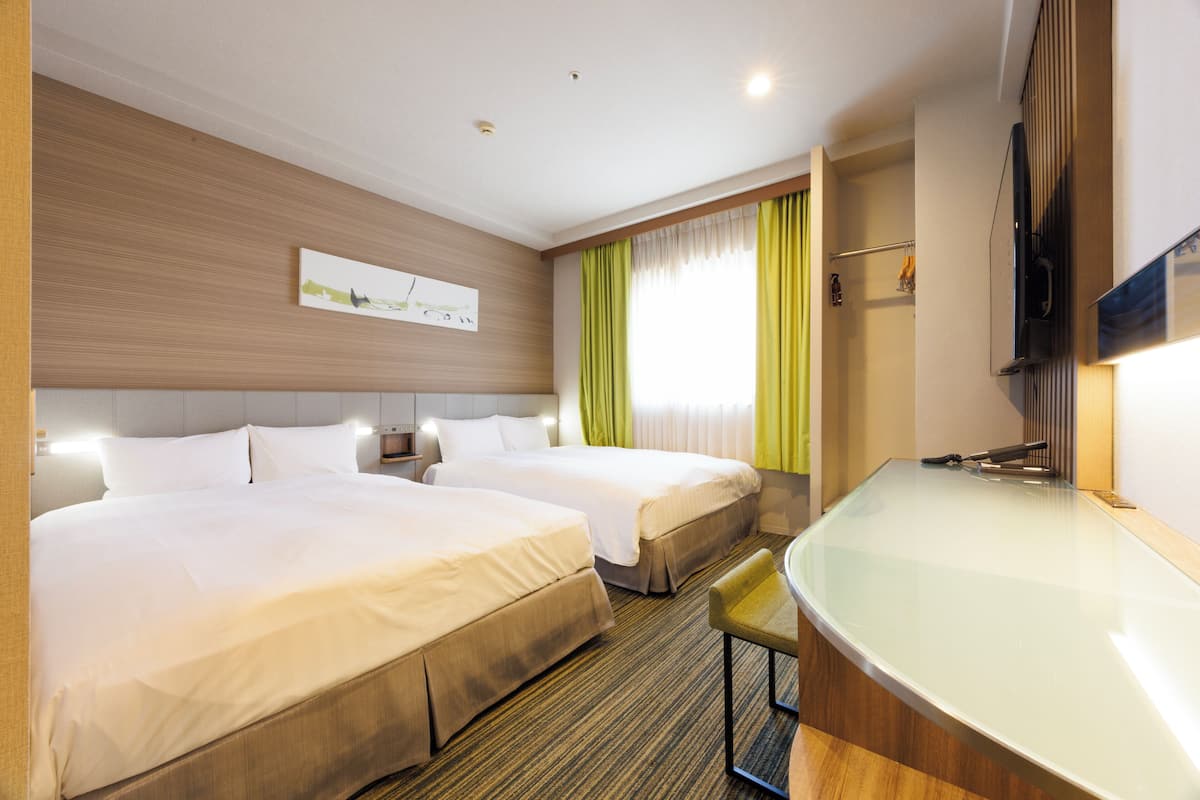 A hotel room with two beds, a glass-enclosed bathroom, and a flat-screen TV.