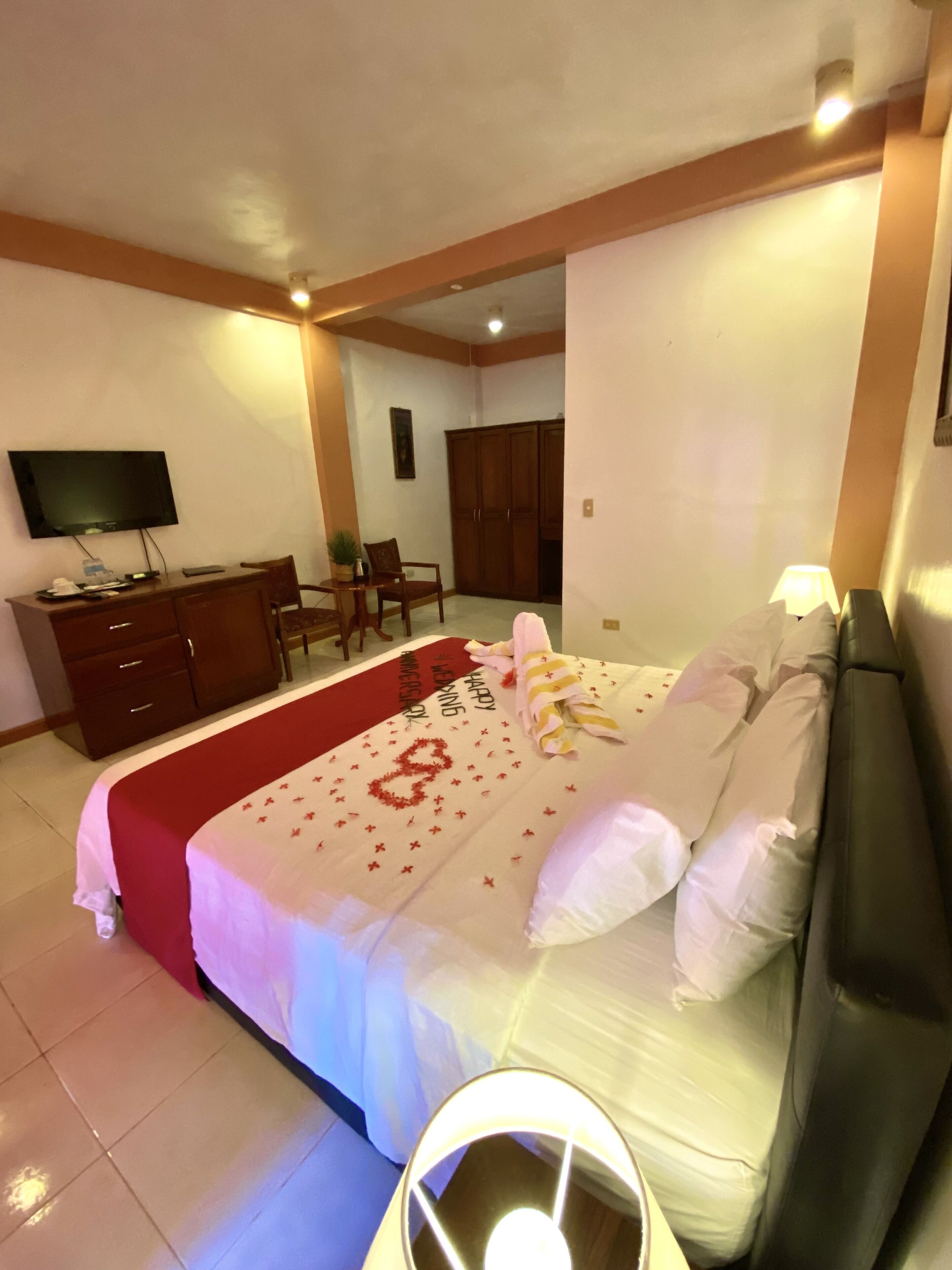 Una habitación de hotel con una cama, televisor, escritorio y armario.