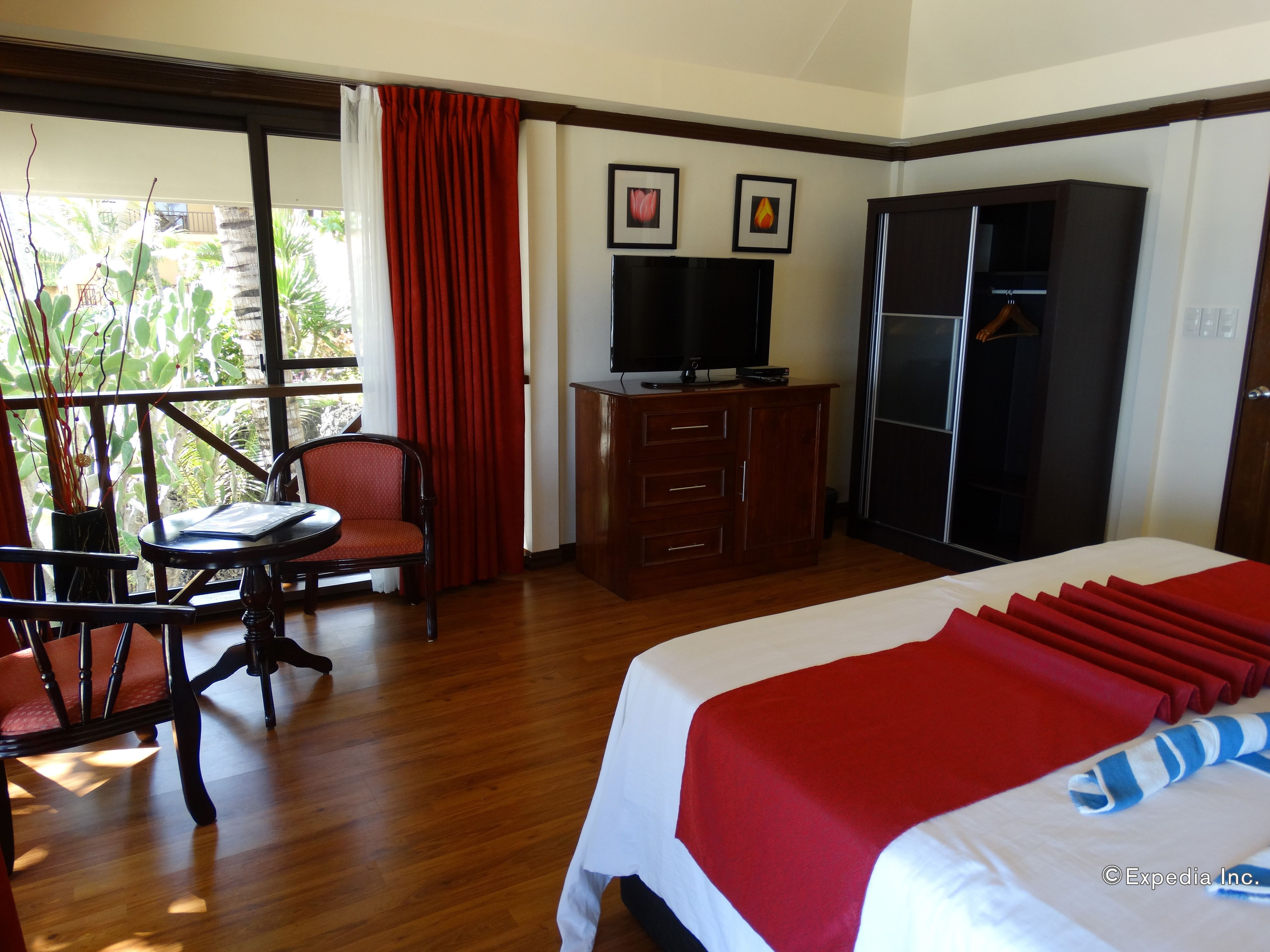 A hotel room with a bed, a desk, a chair, a TV, and a wardrobe.