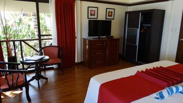A hotel room with a bed, a desk, a chair, a TV, and a wardrobe.