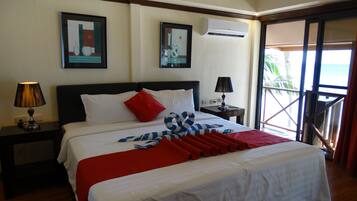 A hotel room with a bed, two bedside tables, an air conditioning unit, and a balcony with a view.