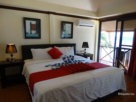 A hotel room with a bed, two bedside tables, an air conditioning unit, and a balcony with a view.