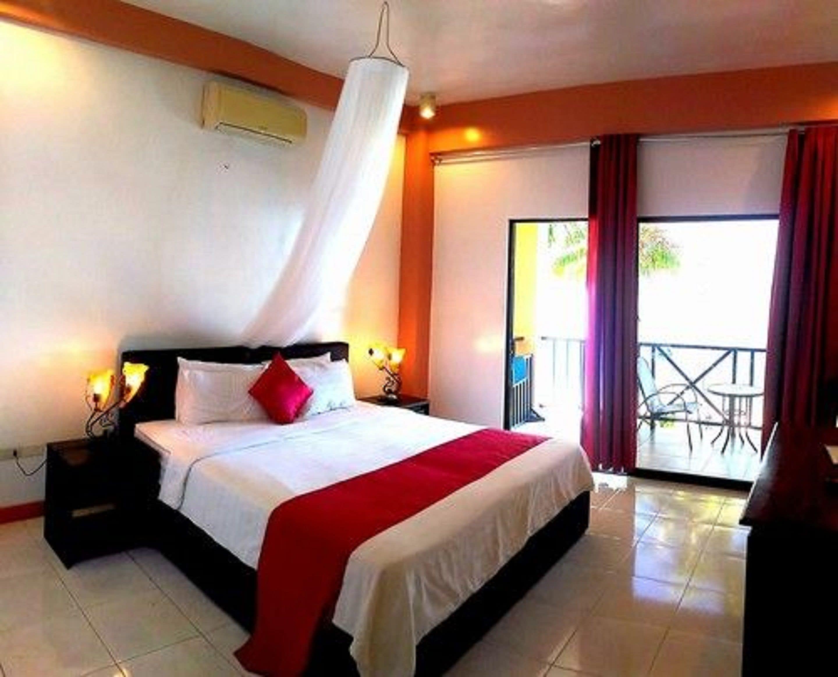 Una camera d'albergo con un letto, lampade ai comodini, una tenda e vista all'esterno.
