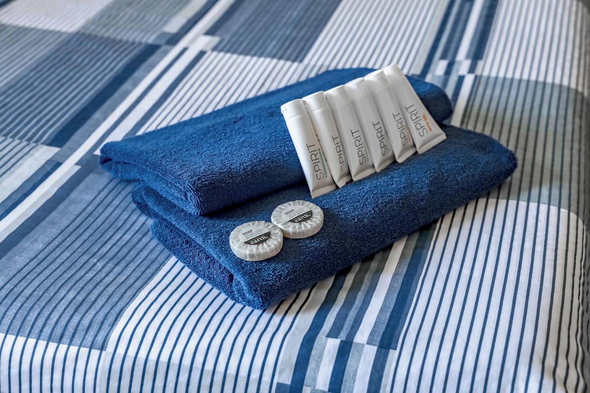 Una toalla azul doblada con cuidado y dos pastillas de jabón sobre un edredón a rayas.