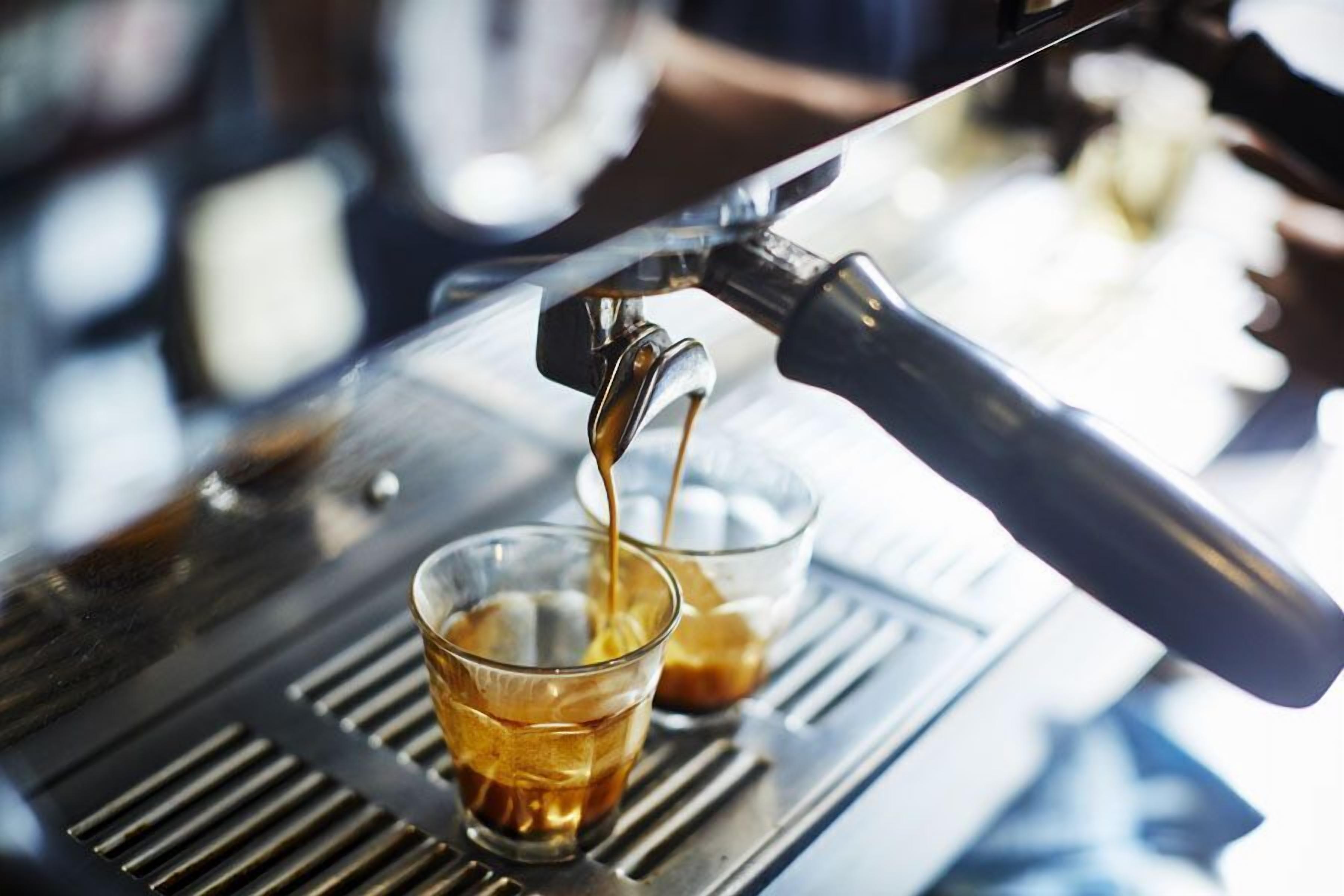Una máquina de café sirve espresso en una taza de vidrio.