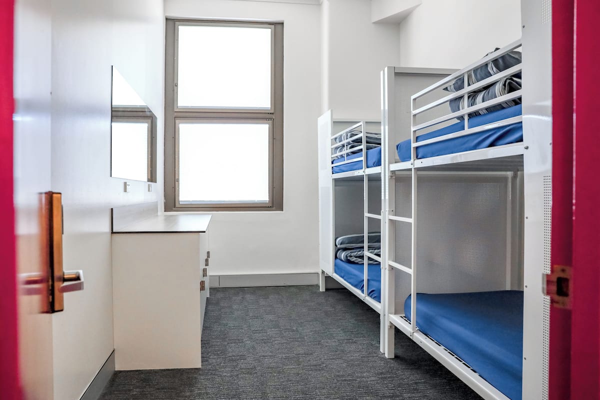 Un dormitorio con literas, un escritorio y una ventana.