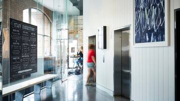 A modern interior with a glass wall displaying staff suggestions, a bench, and an elevator.