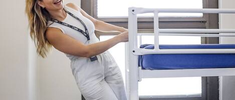 Una cama litera con una maleta y una persona recostada en ella.