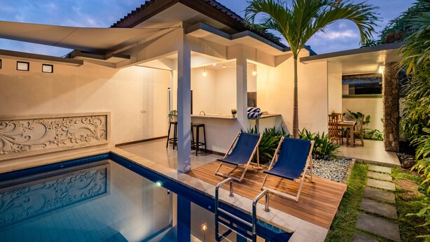 Un área de piscina moderna al aire libre con sillones de descanso, una pérgola y un comedor con vistas a la piscina.