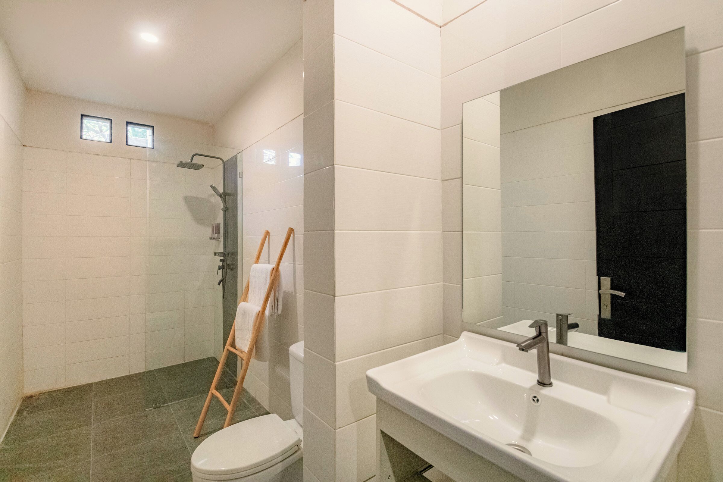 Une salle de bain moderne avec un lavabo blanc, un miroir et une douche.