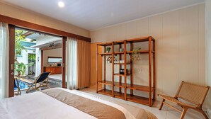 Habitación de hotel con cama, armario de madera, una silla y vista a un área de piscina exterior.