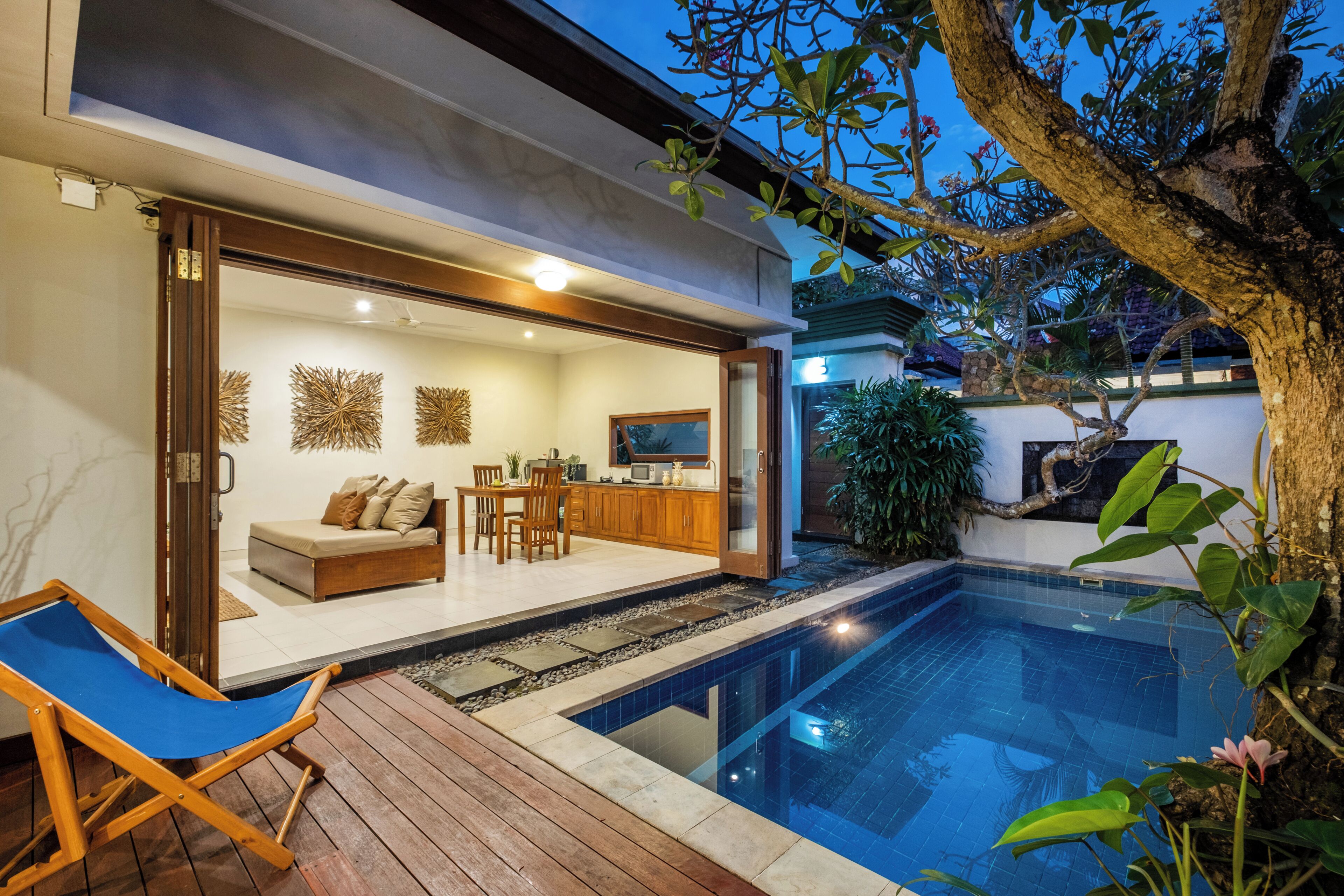 A modern house with a swimming pool, wooden deck, and a dining area.