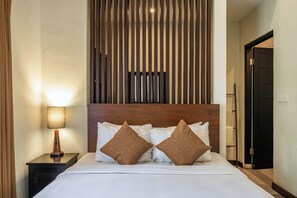 A hotel room with a bed, a nightstand with a lamp, and a wooden headboard. - Villa Kisaraa (Kerobokan)