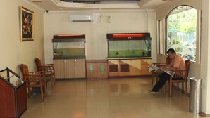A reception area with a fish tank, wooden chairs, and a trash can. - Batam Star Hotel (Batam)