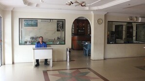 A lobby with a reception desk, a clock, and a large window. - Batam Star Hotel (Batam)