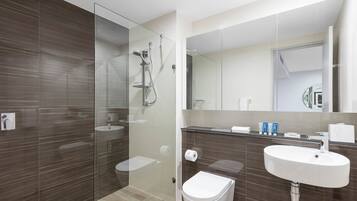 A modern bathroom with a glass-enclosed shower, a white sink, and a toilet.