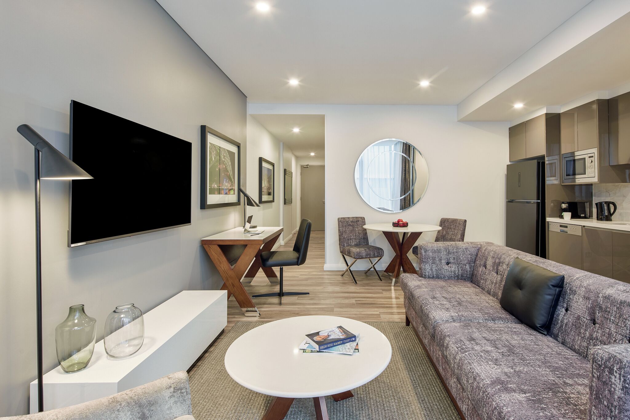 Una sala de estar moderna con sofá, mesa de centro, televisor y una zona de comedor con sillas y mesa.