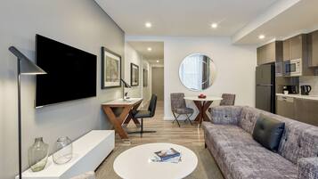 Una sala de estar moderna con sofá, mesa de centro, televisor y una zona de comedor con sillas y mesa.