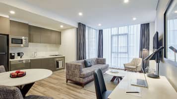 Une chambre d’hôtel moderne équipée d’une kitchenette, d’un canapé, d’une table à manger et d’un bureau avec un ordinateur portable.