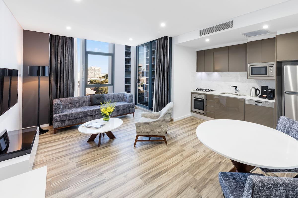 Un apartamento moderno con sala de estar, sofá, sillón, mesa de comedor y cocina.