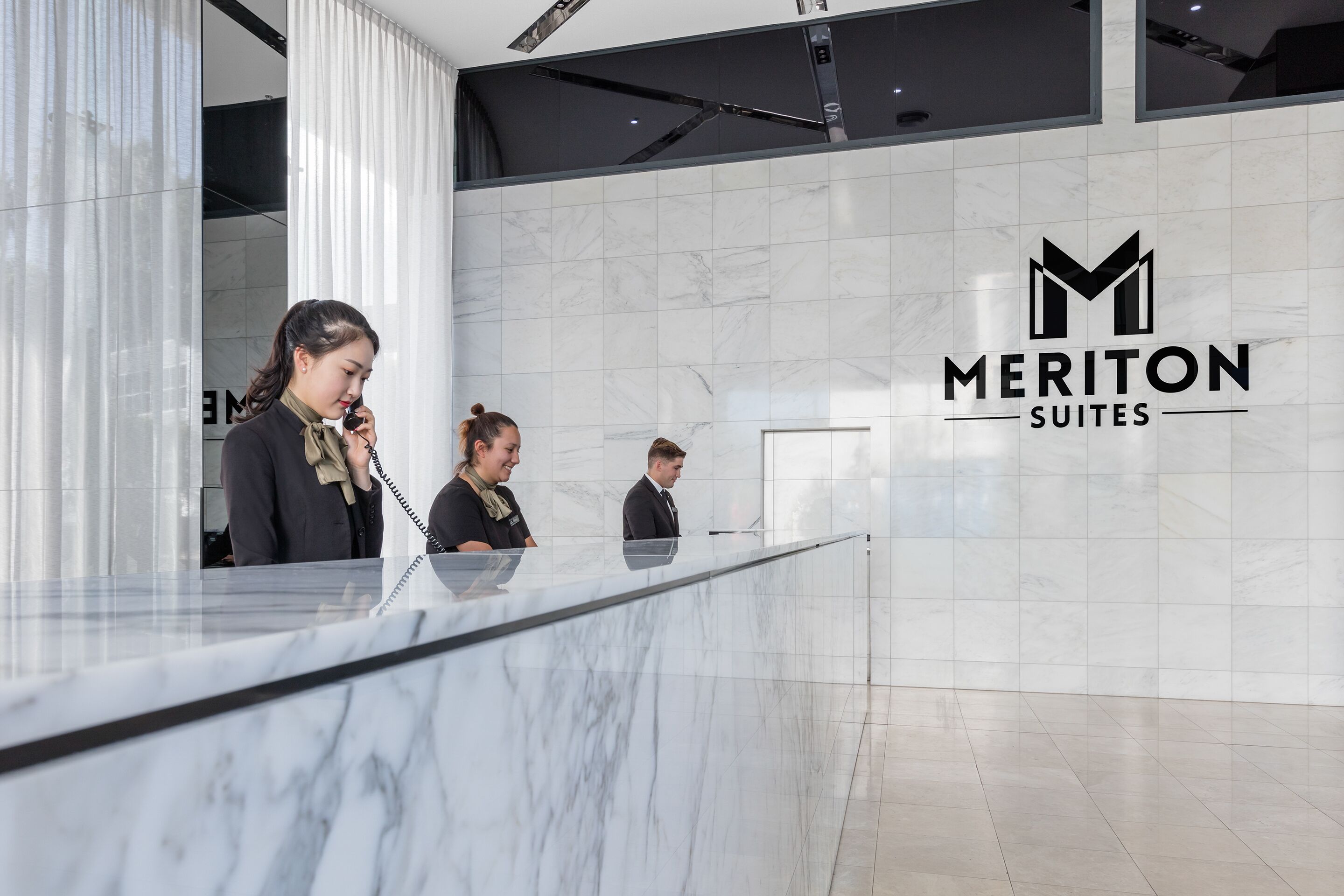 A reception desk with a marble surface and a logo for Meriton Suites.