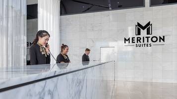 A reception desk with a marble surface and a logo for Meriton Suites.