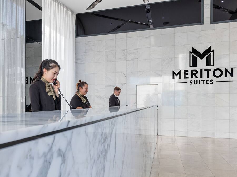 A reception desk with a marble surface and a logo for Meriton Suites.