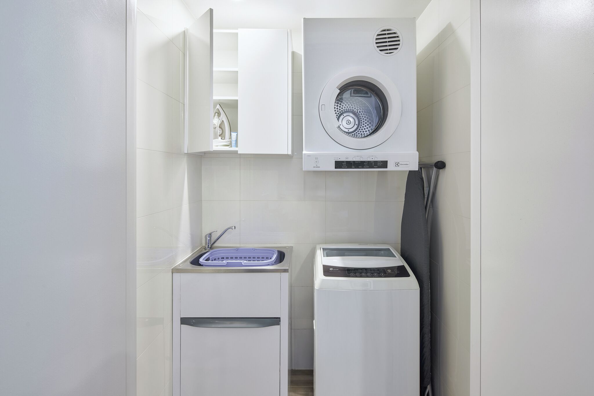 A compact laundry area with a washing machine, a dryer, and a sink.