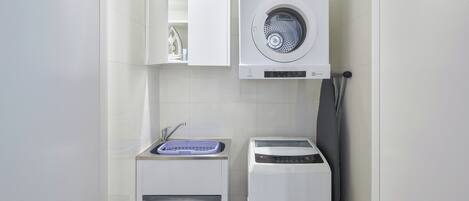 A compact laundry area with a washing machine, a dryer, and a sink.
