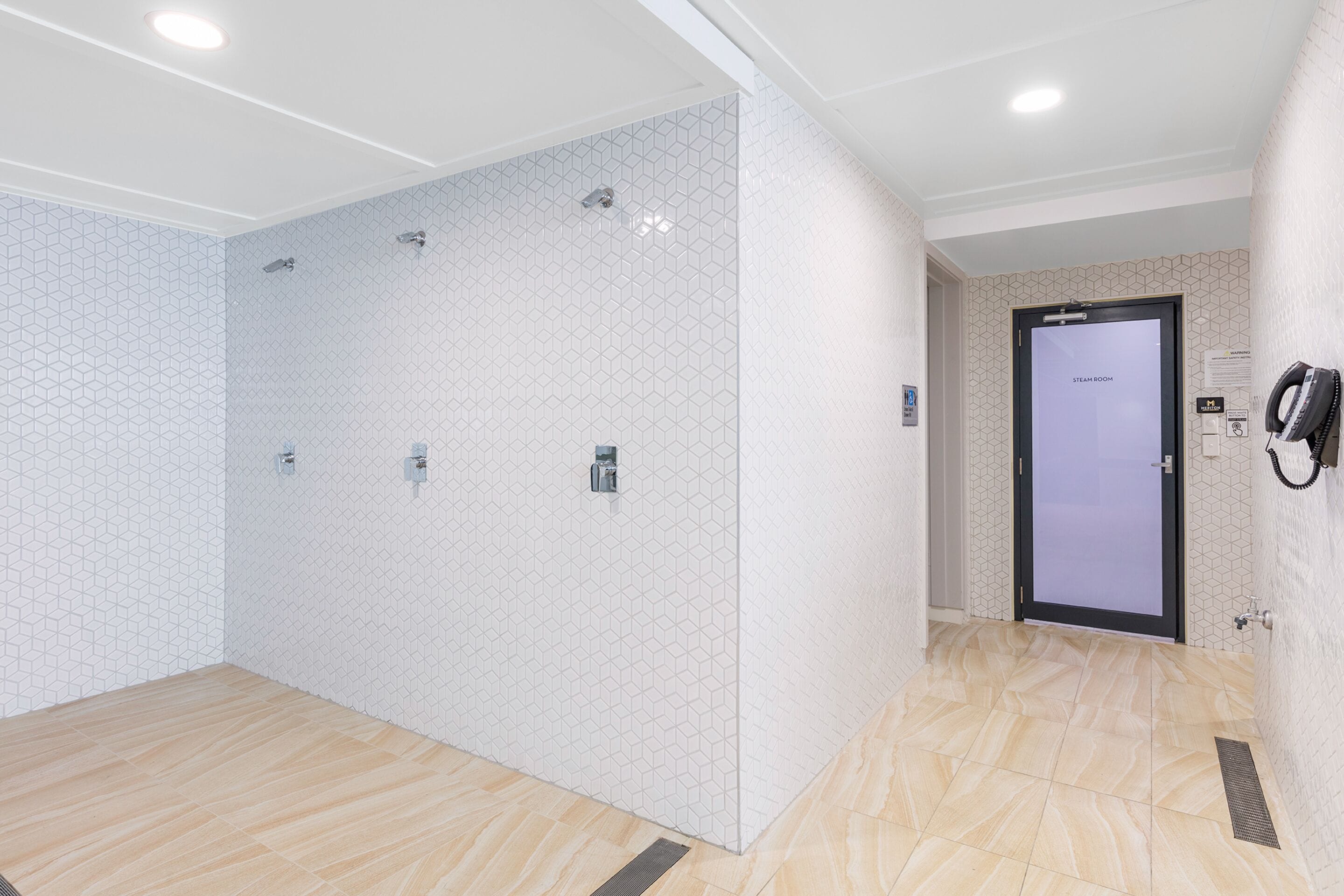A modern bathroom with hexagonal patterned tiles, a shower area, and a steam room door.
