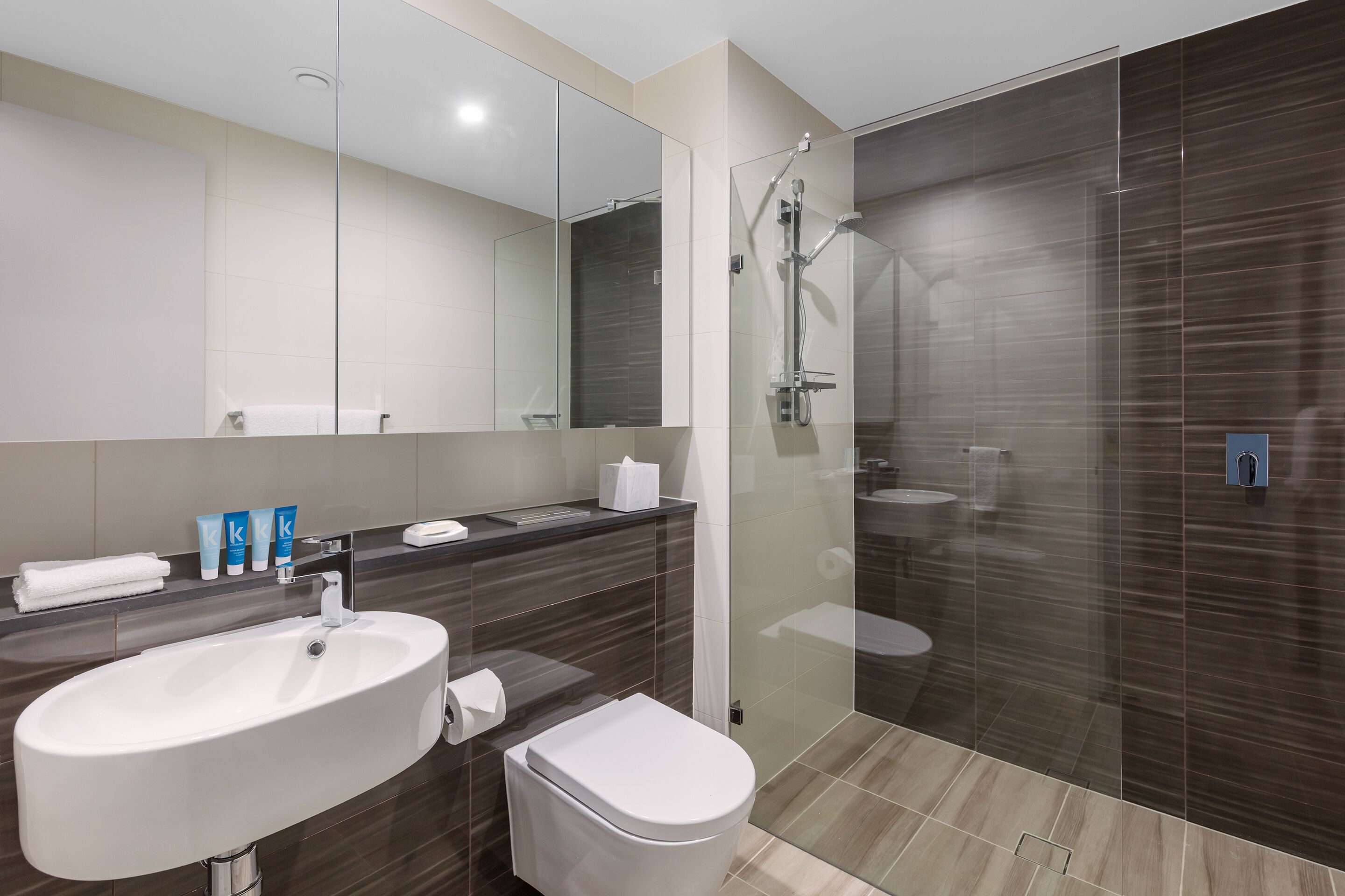 Un baño moderno con un lavamanos grande, espejo y ducha.