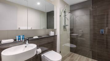 Un baño moderno con un lavamanos grande, espejo y ducha.